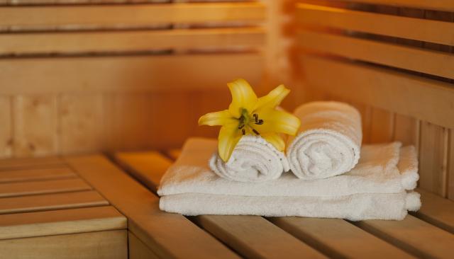 Handtücher mit Blüte auf einer Holzbank in der Sauna